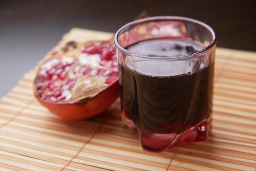 glass on pomegranate juice and fresh fruits on red background