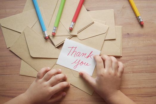 child hand holding thank you letter on table ,