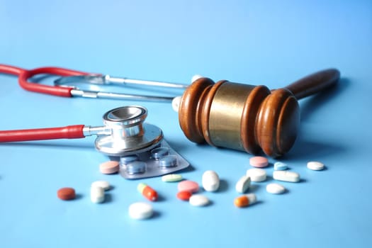 Top view of gavel, stethoscope and pills on white background.