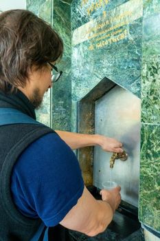 Man Pouring mineral thermal water into the disposable cup at the pump-room, close-up. narzan spring in Kislovodsk, Russia. High quality photo