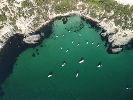 Sea landscape with rocky coastline on sunset time with cloudy sky. Yachts in the Sea on a background of rocky shores. The concept of perfect place for summer travel and rest.