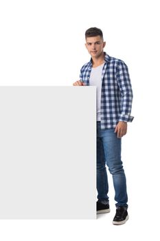 Young happy casual man holsing blank banner isolated on white backgrounf