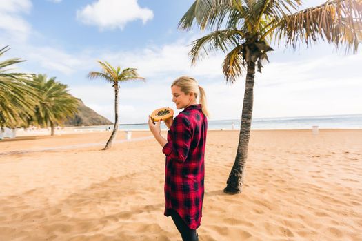 woman holds papaya on the beach