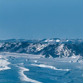 Winter wonderland and Christmas fantasy landscape. Frozen sea coast and mountains covered with snow as holiday background.