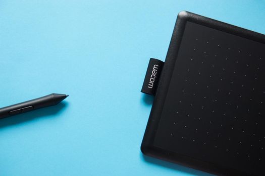 Tver, Russia - February 3, 2020 Top view of Wacom graphic tablet on blue background. Space for text. Selective focus.