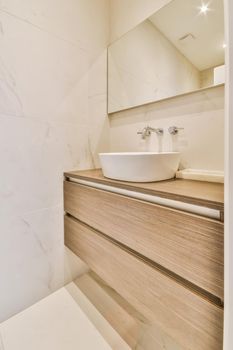 Luxurious bathroom with a beautiful hanging wooden chest of drawers with a sink