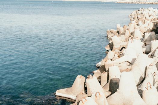 The seashore is reinforced with concrete tetrapods. Protection of the shore from blurring. Sea waves. Concrete tetrapod breakwaters lie all along the coast.