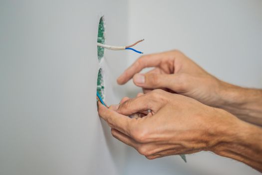 Master electrician installs a socket in the house.