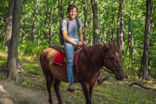 handsome man ride on the black horse in green forest.