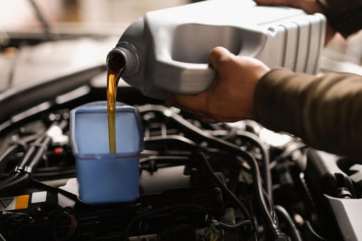 A man pours engine oil into a car, close-up. Service at a service station, vehicle operation. Selection of oil for the automobile