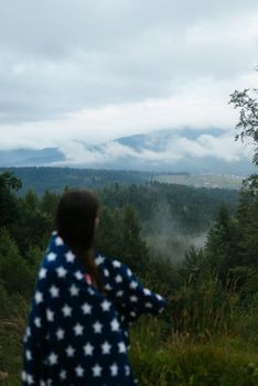 Woman standing on top of a hill, against the background of a valley in the fog