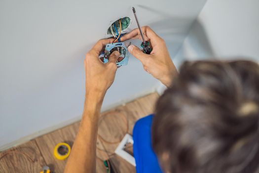 Master electrician installs a socket in the house.