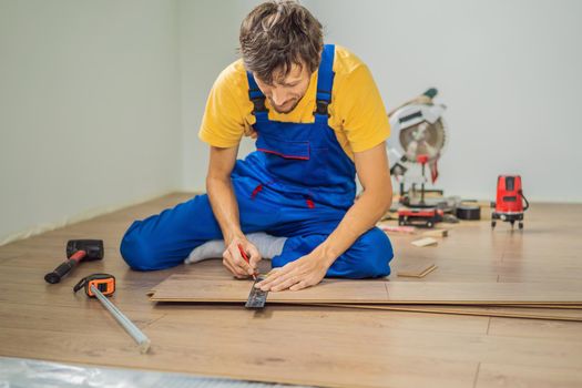 Man installing new wooden laminate flooring on a warm film floor. Infrared floor heating system under laminate floor.