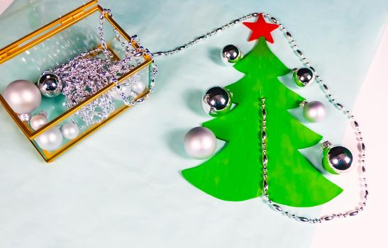 silver ornaments come out of a glass and gold casket and decorate a flat Christmas tree on a black and blue background. minimalistic christmas decoration concept. High quality photo