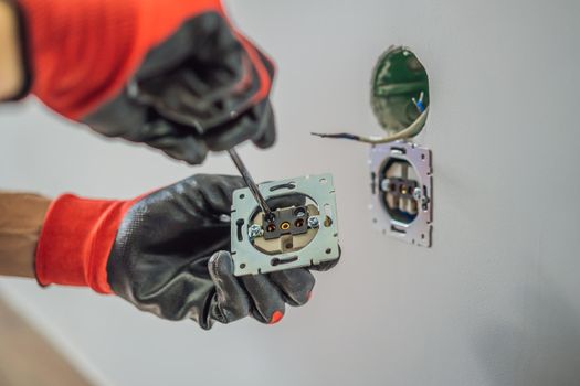 Master electrician installs a socket in the house.