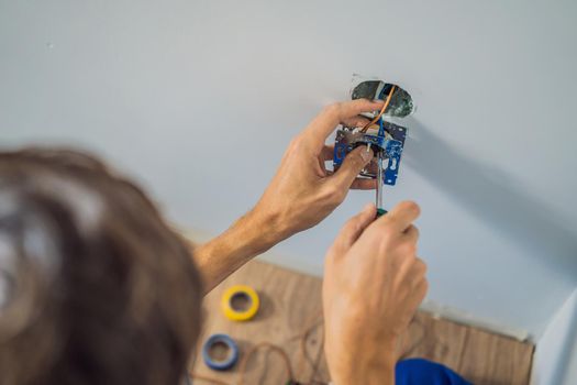 Master electrician installs a socket in the house.