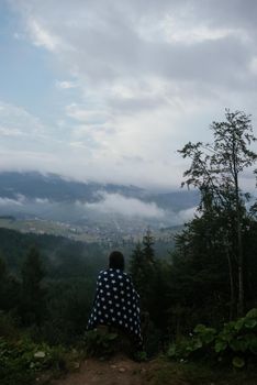 Woman on top of a hill, against the background of a valley in the fog