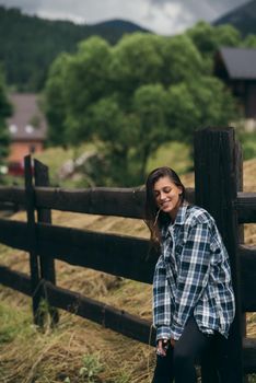 A young attractive Caucasian female stand by a fence and posing at camera