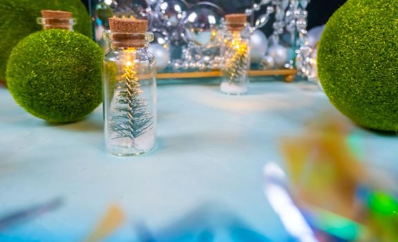 magic garland - Toy Christmas trees in glass jars and green grass balls, on a blue background. a glass casket with silver ornaments. magical holiday mood. High quality photo