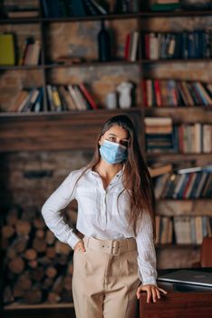 Young woman in protective mask on the background of bookshelves