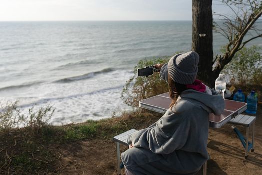 Woman takes a photo on a smartphone of the seascape