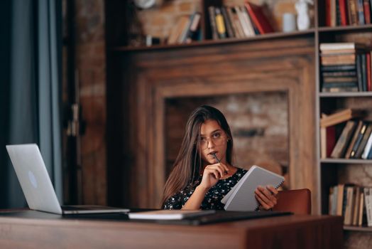 A woman's hand writing down on a white blank notebook on table.