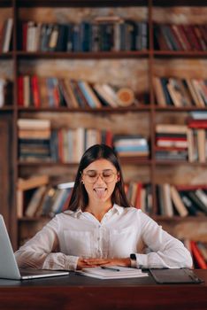 Young businesswoman sitting at desk and working. Smiling and looking back at camera