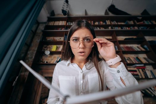 Young woman holding an open book in hands and looking at the camera