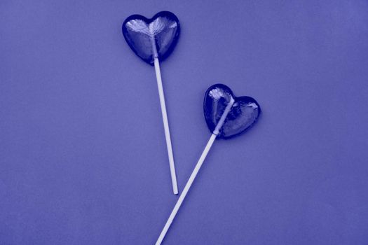 Purple lollipops in the form of hearts on a purple background. The concept of Valentine's Day. Demonstrating the colors of 2022 - Very Peri.