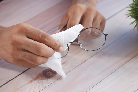 Close up of man hand cleaning eyeglass .