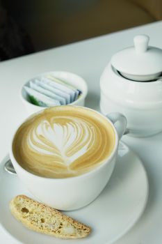 a cup of late coffee with flower shape design on top at cafe .