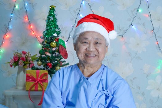 Asian senior or elderly old lady woman patient with Santa Claus helper hat in Christmas and new year celebration festival holiday party in hospital.