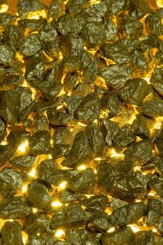 Gold nuggets as a background with golden light from below. close-up