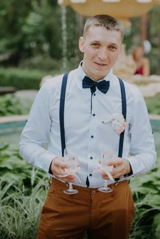 Handsome groom holding two glasses of champagne. Handsome happy man in elegant suit holding holding two glasses of champagne and celebrating his wedding day.