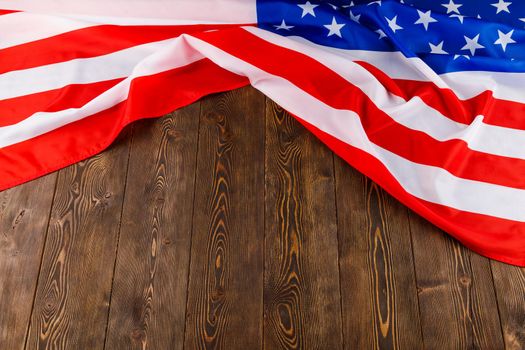 crumpled usa flag on flat textured wooden surface background.