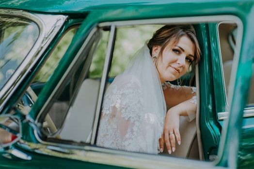 Car woman happy in old retro vintage car. Young woman driving on road trip on beautiful sunny summer day. Wedding bride sit on red retro car after wedding. honeymoon concept.