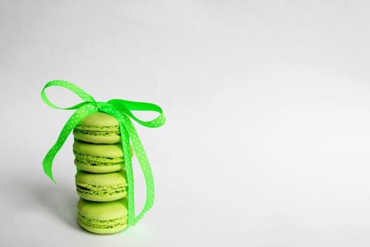 Green macaroon cakes with bright ribbon. Nice design for any purpose. White background. Place for your text. A gift for your beloved. Surprise for the holiday.