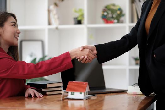Estate agent and customer shaking hands after finished contract after about home insurance and investment loan.