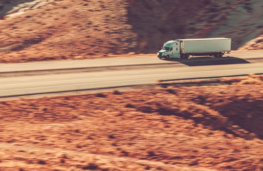 Speeding Modern Semi Trailer Truck on Interstate Highway 70, Utah State USA. Rocky Formations Landscape.