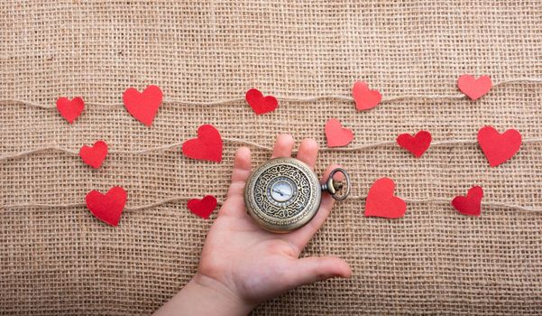 Love concept with pocket watch and  paper hearts on threads