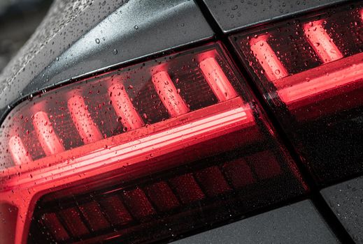 Modern Vehicle Wet From Car Washing Rear LED Light Close Up. Automotive Theme.