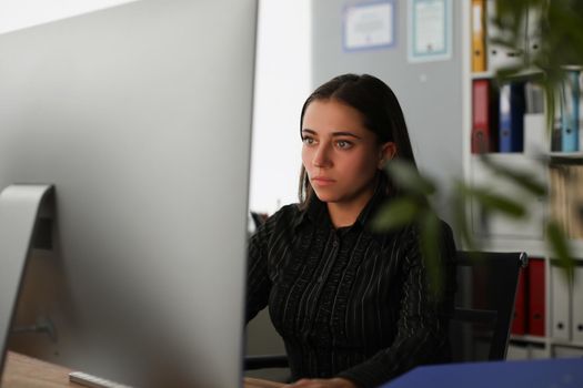Portrait of young office worker stare at computer screen, search information online. Corporate clerk late at work, prepare report alone. Business concept