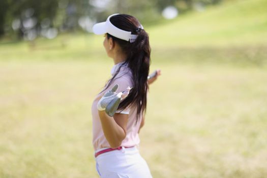 Close-up of professional woman golf player pose with golf club on field. Green grass for perfect competition game. Hobby, sport, physical activity concept