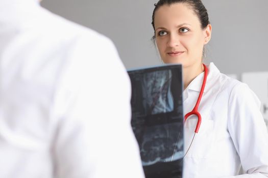 Portrait of female doctor discuss with colleague patient x ray result. Worker hold scan result of clients checkup. Medicine, treatment, diagnostic concept