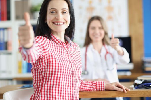 Portrait of happy woman patient show thumbs up gesture, woman healthy after treatment. Doctor support patient and celebrate with her. Win disease concept