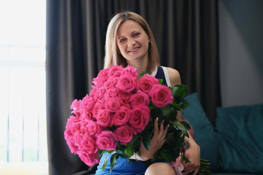 Portrait of beautiful young woman get bouquet of flowers on birthday or anniversary. Pink roses present from husband or friend. Attention, beauty concept