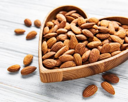 Almonds in brown bowl on wooden background