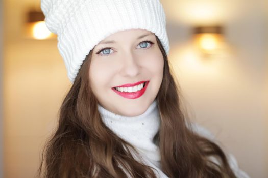 Christmas, people and winter holiday concept. Happy smiling woman wearing white knitted hat as closeup face xmas portrait.