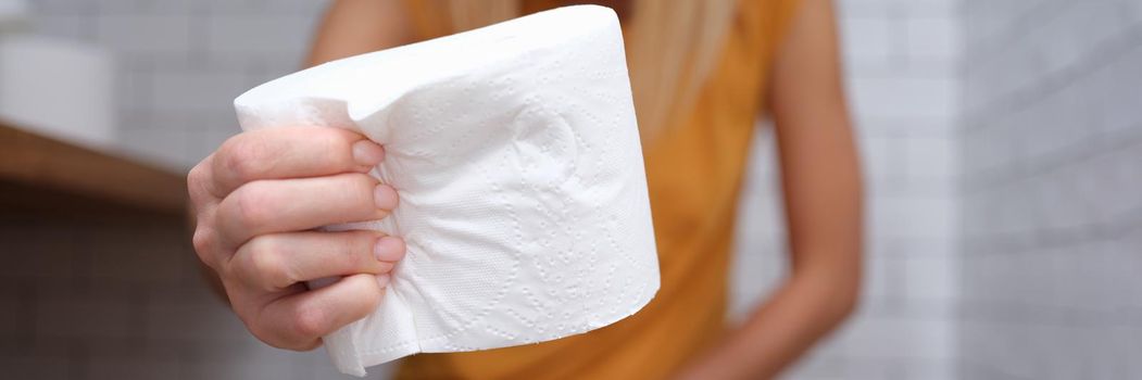 Woman is sitting on t toilet and holding roll of toilet paper. Constipation reasons concept