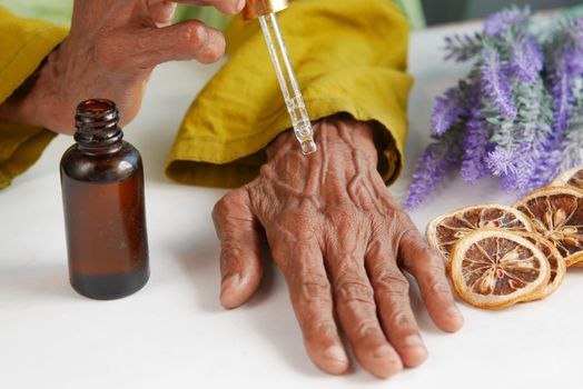 senior women applying essential oils on hand ,